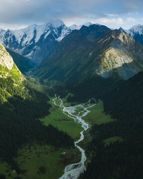 Aerial view of Boris Yeltsin Peak towering over the lush Jety-Oguz valley, with a winding glacial river and dense coniferous forests in Jety-Oguz, Issyk-Kul Region, Kyrgyzstan.