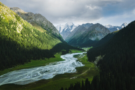 Aerial view of Boris Yeltsin Peak above the lush Jety-Oguz valley with a winding glacial river, dense forests, and dramatic mountain slopes in Jety-Oguz, Issyk-Kul Region, Kyrgyzstan.