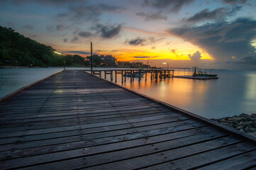 Obraz premium The wooden pier extending into the sea serves as a harbor in the mornings at sunrise.