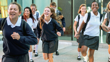 Fototapeta premium Joyful students running outside school