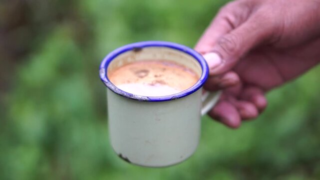 Detailed view of enjoying a warm traditional cup of coffee outdoors, symbolizing tranquility, eco-friendly adventure, and relaxation in the countryside.