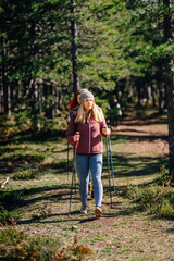 Obraz premium Women hiking forest trail using trekking poles
