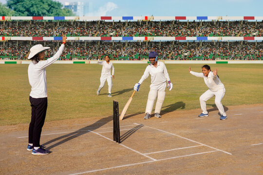 Umpire signals out as cricketers celebrate a successful appeal