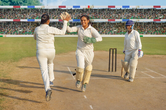 Cricketers celebrate with a high-five on the field