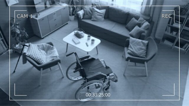 CCTV security camera footage showing empty living room in nursing home with wheelchair standing in center. Clip senior care safety, home surveillance, or medical monitoring videos