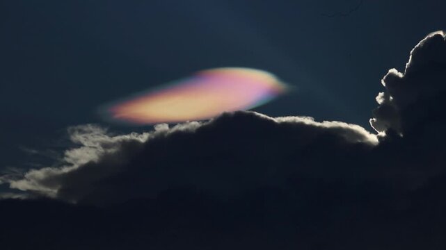 Dark cloud iridescent cloud sky silhouette dramatic evening nature atmospheric colorful moody scene with glowing iridescent cloud floating above dark clouds, creating mysterious atmospheric