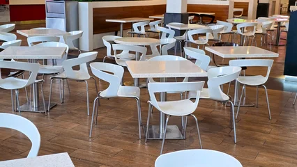 Fotobehang Horeca Empty modern restaurant interior features white designer chairs and square tables with no people.  © ЮРИЙ ПОЗДНИКОВ