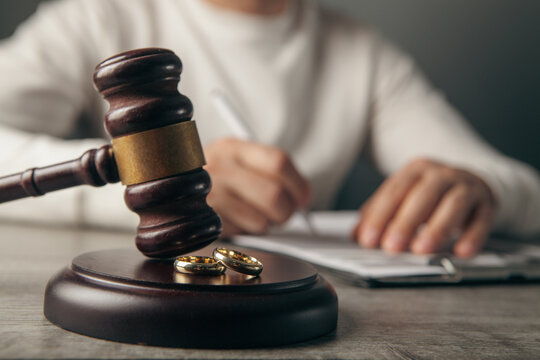 Judge gavel and wedding rings on table. Divorce concept.