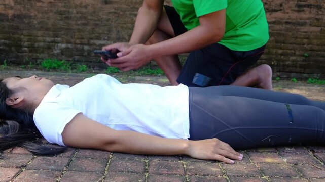 Person performing chest compressions on an unresponsive woman for resuscitation procedure