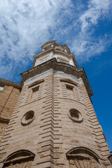 Fototapeta premium Low-angle view of the Levante Tower (Clock Tower) of Cádiz Cathedral, Spain, showcasing its baroque architecture against a deep blue sky.