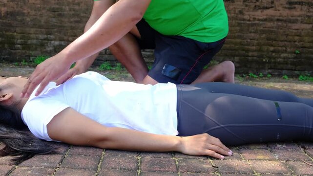 Person performing chest compressions on an unresponsive woman for resuscitation procedure