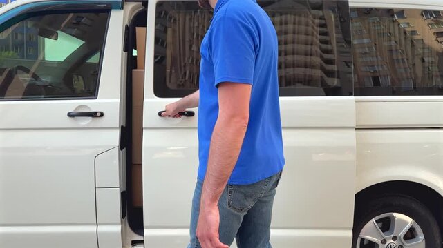 Delivery driver walks alongside van in urban environment, ready to handover packages to customers. Efficient delivery concept captures modern logistics in action