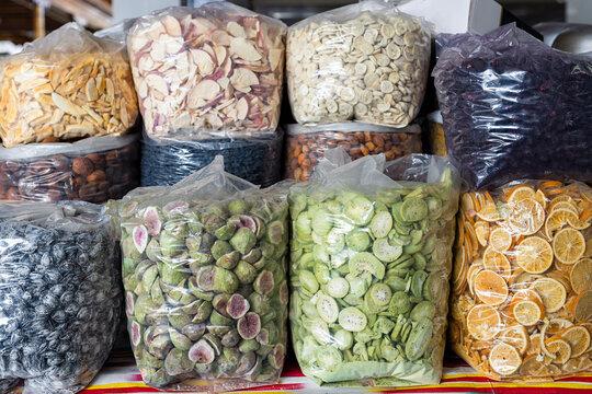 Dried fruits and nuts in plastic bags displayed at Siab bazaar in Samarkand. Colorful variety of figs, kiwi, orange slices, apples, raisins, and almonds for sale at a traditional market.