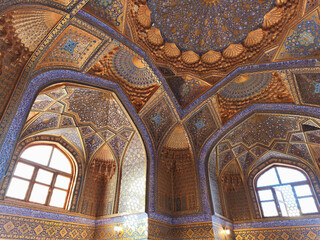 Obraz premium Ornate interior of Ak Saray Mausoleum in Samarkand featuring golden muqarnas and blue tilework. Ideal for travel publications, cultural heritage materials, and architectural studies.