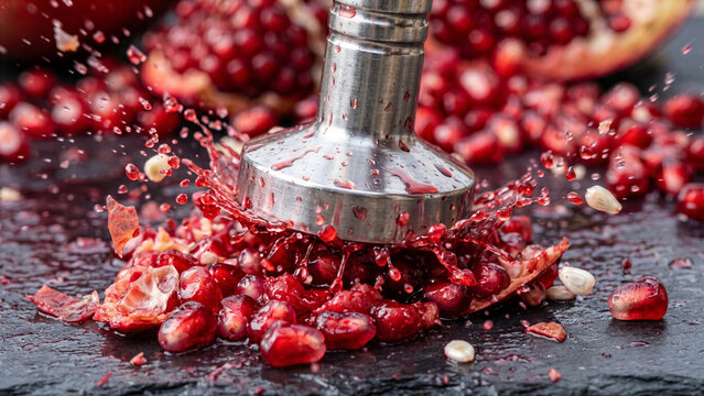 Macro view of fresh ripe pomegranate arils bursting under tamper with rich red juice explosion splash
