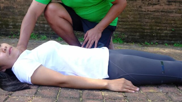 Person performing chest compressions on an unresponsive woman for resuscitation procedure