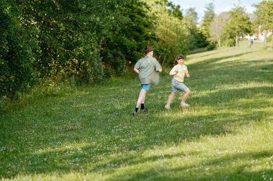 Children running across open grassy park with copy space