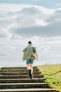 Teenage boy running up outdoor steps toward hilltop