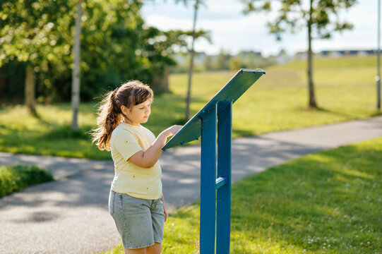 Young girl reading information board in neighborhood green space