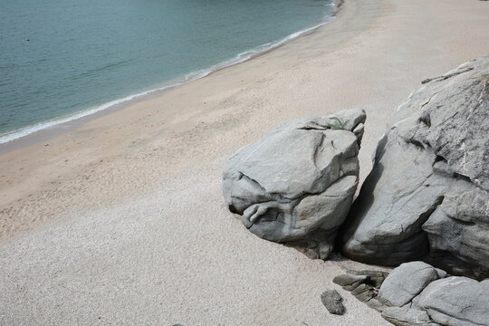 Grey rocks on a sandy golden shore