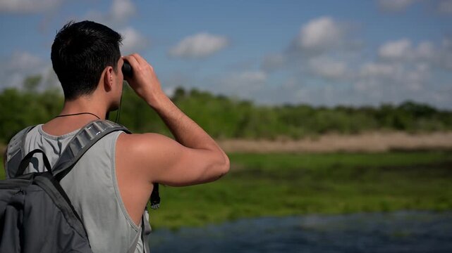Young man exploring nature with binoculars with copy space