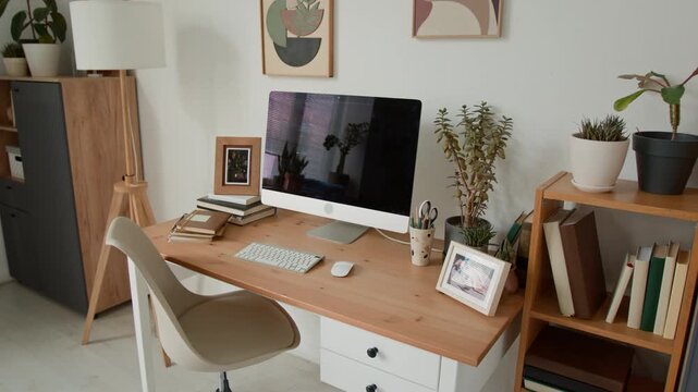 Modern home office workspace standing empty with computer, keyboard, and potted plants on wooden desk. Ideal for remote work, freelance business, and online education commercial videos