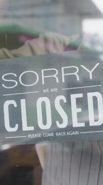 Vertical Screen : Young Asia girl wear face mask turning sign from open to closed sign on glass door cafe after coronavirus quarantine. Owner small business, food and drink, business financial crisis.