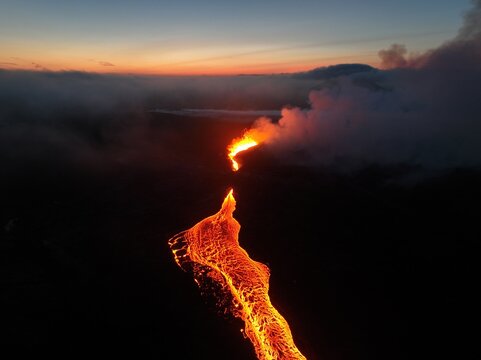 Aerial view of the Litli-Hrutur volcanic eruption with glowing lava flowing through the dark landscape at twilight in Grindavik, Grindavikurbaer, Iceland.