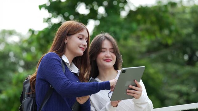 Two female university students use a tablet together outdoors, sharing ideas and learning through digital technology.