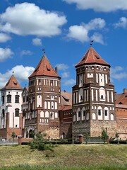 Fototapeta premium Historic medieval brick castle towers under blue sky with white clouds