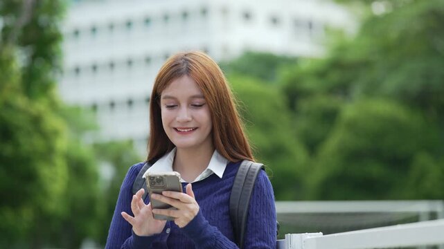 Young female student using a smartphone outdoors on campus, enjoying mobile learning and digital communication.