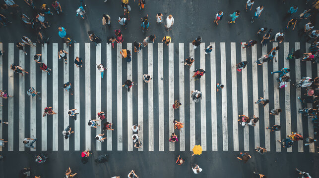Aerial view of busy pedestrian crossing with diverse crowds navigating the streets in a vibrant urban setting.