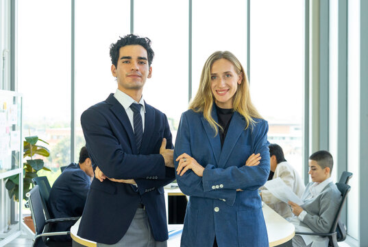 Portrait of two businesspeople standing with arms crossed in modern office