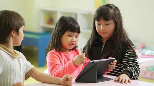Young children use a tablet together during a classroom activity, building teamwork and digital learning skills.
