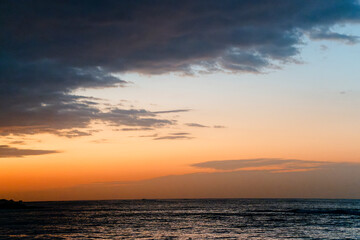 Obraz premium Dramatic Sunset Coastline with Golden Light Over Calm Ocean Horizon