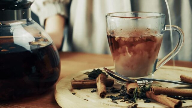 Pouring Milk Into Glass Cup Of Hot Herbal Tea. Adding Cream Into Warm Beverage Infusion. Organic Drink