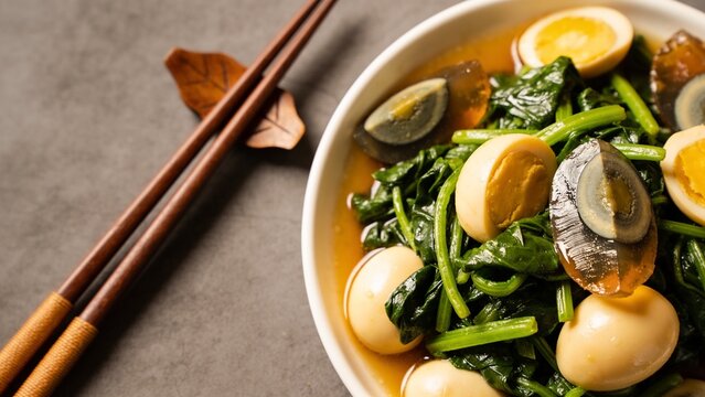 Chinese Spinach with Salted Eggs and Century Eggs in a dish with chopsticks on grey background