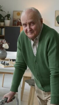 Portrait of senior man leaning on walker and smiling at camera in assisted living facility. Footage suits senior care services and healthcare marketing, vertical