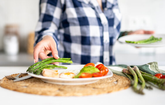Girl Preparing A Healthy Breakfast With Egg, Fish, Asparagus, And Cherry Tomatoes