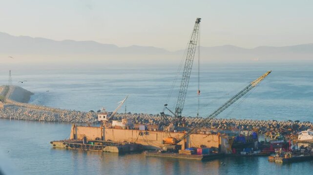 Heavy duty crane barge constructing harbor rock breakwater