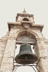 Obraz premium A low angle view of the ancient bronze bell hanging inside the stone arch structure at the top of El Miguelete tower of the Valencia Cathedral landmark building historical monument in Valencia Spain
