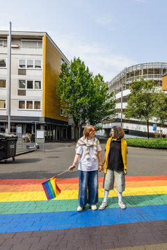 Friends walking on a rainbow crosswalk during pride parade