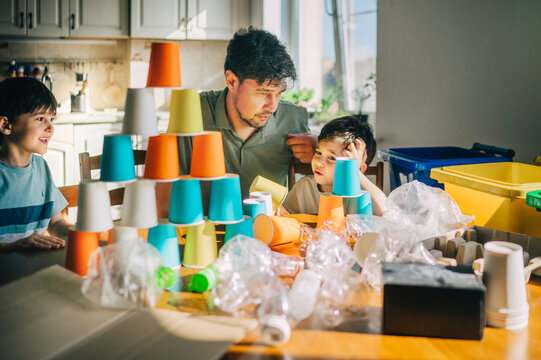 Father and family sorting plastic waste and playing indoors