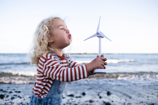 Boy blowing wind turbine toy at beach