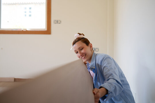 Woman installing laminate flooring indoors during renovation