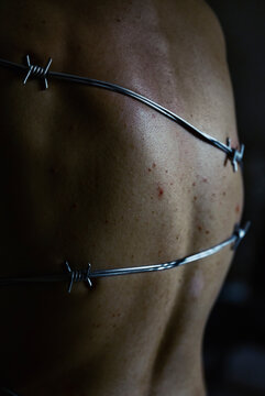 Bare back wrapped in sharp barbed wire depicting abuse and pain
