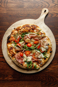 Craft pizza with prosciutto, tomatoes and arugula isolated.