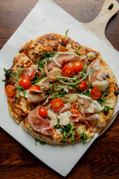 Craft pizza with prosciutto, tomatoes and arugula isolated.