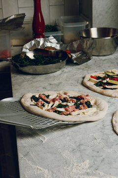 A pizza maker places a pizza for further baking in the oven