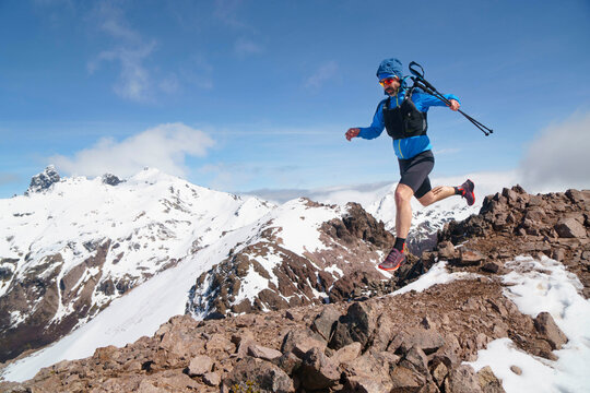 Male athlete trail running down snowy mountain